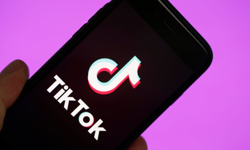 Visual representation of TIktok logo on a smart phone and pink background