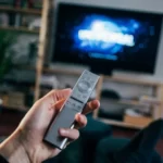 hand holding a remote in front of tv