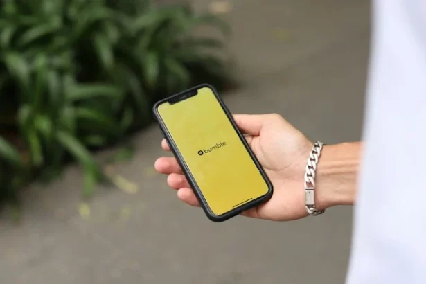 A man holding a phone with Bumble app open