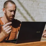 Man sitting on a table with Asus laptop