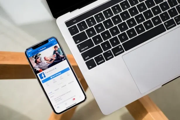 Phone with Facebook open on a table with laptop on side